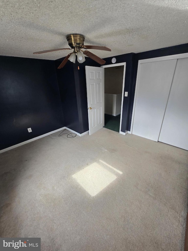 unfurnished bedroom featuring baseboards, carpet, ceiling fan, and a textured ceiling