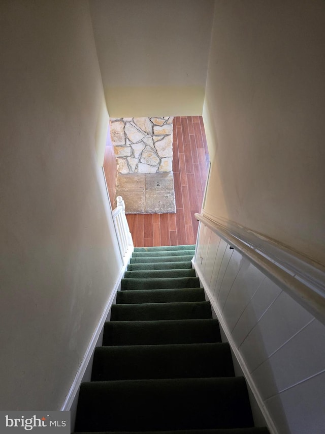 stairs featuring a wainscoted wall and wood finished floors