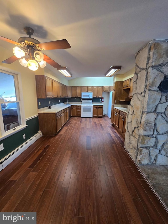 kitchen with brown cabinets, a sink, dark wood finished floors, white appliances, and light countertops