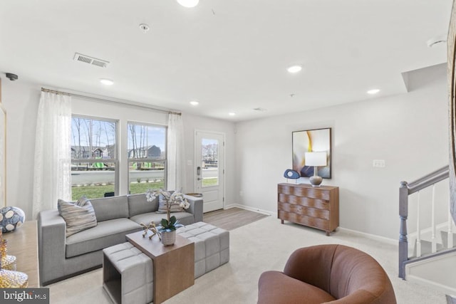 living area with stairway, visible vents, baseboards, recessed lighting, and light carpet