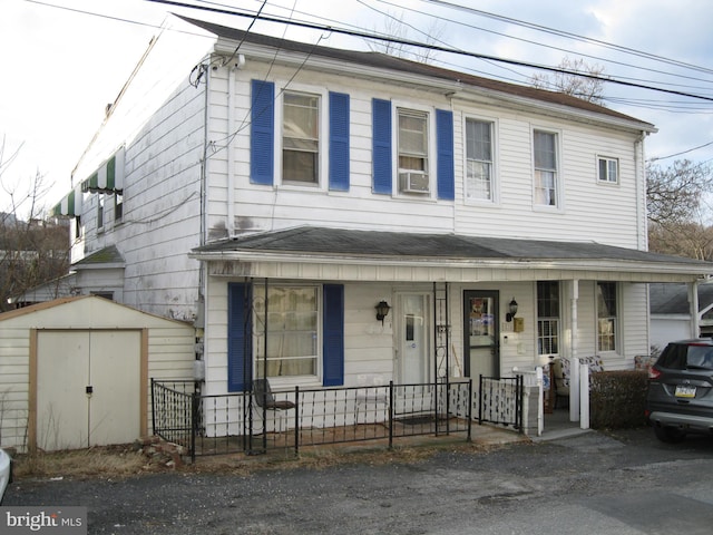 view of front of property with an outdoor structure, cooling unit, covered porch, and a shed