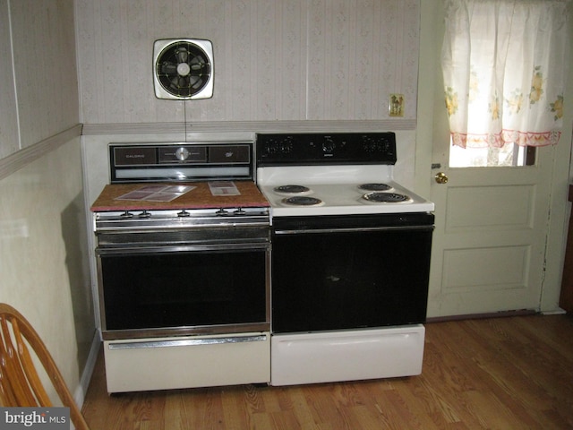 kitchen featuring electric range, black electric range oven, wallpapered walls, and wood finished floors