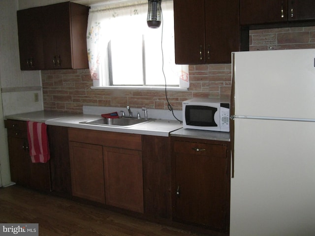 kitchen with white appliances, light countertops, backsplash, and a sink