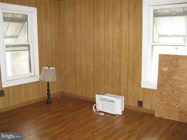 spare room with a wall unit AC, wood finished floors, baseboards, and wood walls