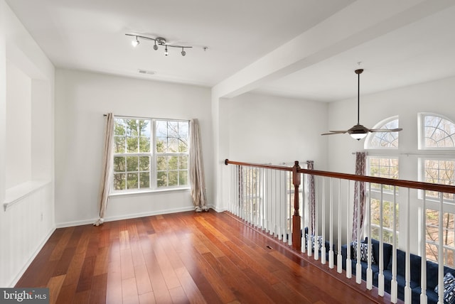 hall with visible vents, baseboards, and wood-type flooring