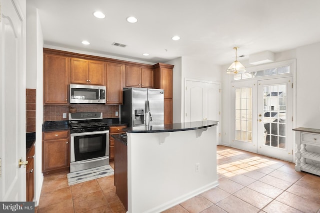 kitchen with dark countertops, brown cabinets, tasteful backsplash, and stainless steel appliances