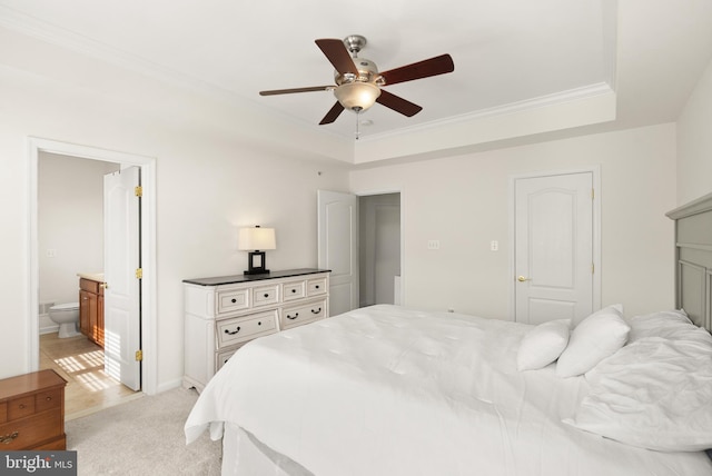 bedroom featuring ornamental molding, ensuite bathroom, a raised ceiling, light colored carpet, and ceiling fan