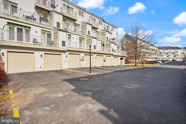 view of building exterior with an attached garage, a residential view, and driveway