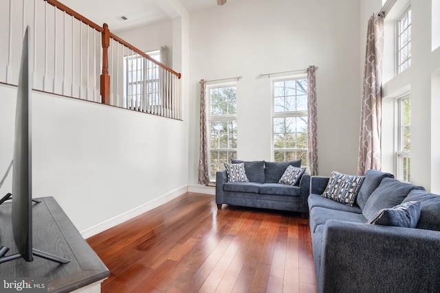 living room featuring hardwood / wood-style floors, a high ceiling, baseboards, and visible vents