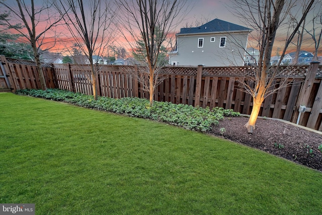 yard at dusk featuring a fenced backyard