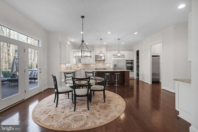 dining space with recessed lighting, baseboards, an inviting chandelier, and dark wood-style floors