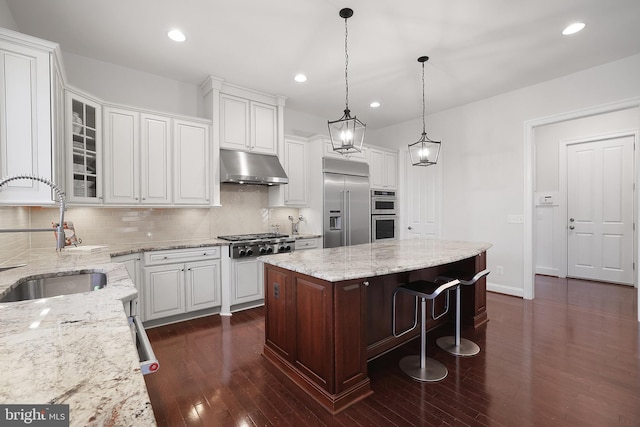 kitchen with dark wood-type flooring, under cabinet range hood, a sink, stainless steel appliances, and white cabinets