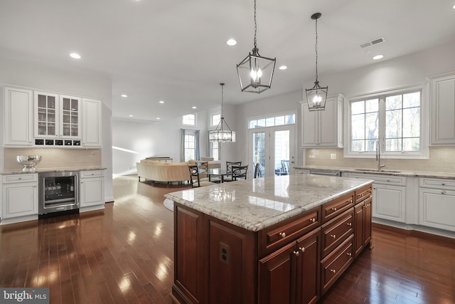 kitchen with dark wood-style floors, visible vents, a sink, wine cooler, and white cabinetry