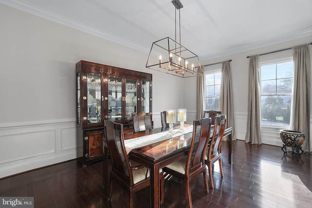 dining area featuring a decorative wall, crown molding, dark wood finished floors, wainscoting, and a notable chandelier