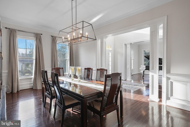 dining room with dark wood-style floors, crown molding, and ornate columns