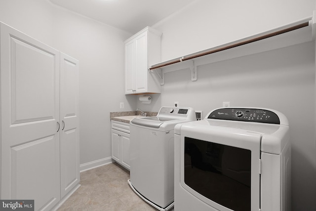 washroom featuring baseboards, washing machine and dryer, light tile patterned floors, cabinet space, and a sink