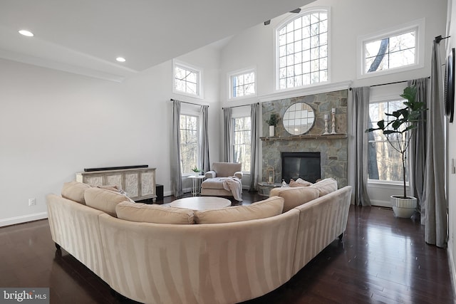 living area featuring baseboards, dark wood finished floors, a high ceiling, recessed lighting, and a fireplace