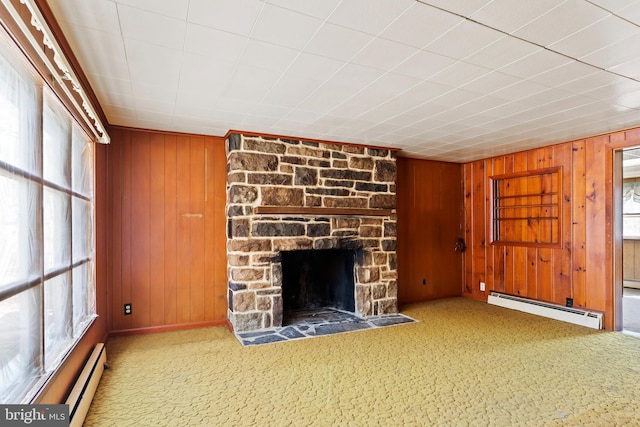 unfurnished living room with wooden walls, carpet floors, a baseboard radiator, a stone fireplace, and a baseboard heating unit