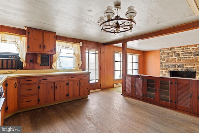 kitchen featuring wood walls, light countertops, baseboard heating, a notable chandelier, and wood-type flooring