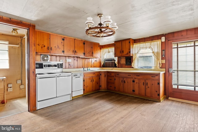 kitchen featuring light countertops, light wood-type flooring, brown cabinetry, a notable chandelier, and white appliances