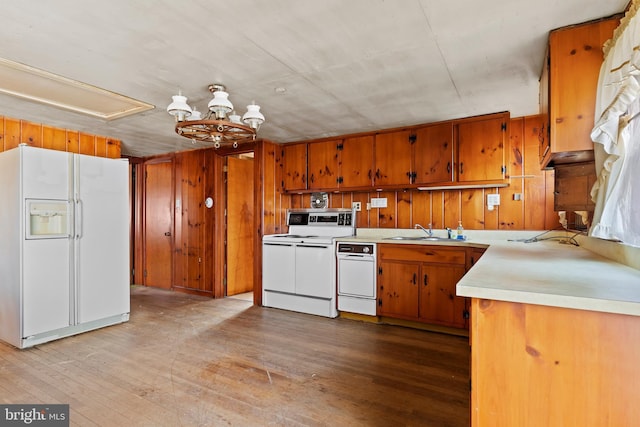 kitchen featuring light countertops, light wood-style floors, brown cabinetry, white appliances, and a sink