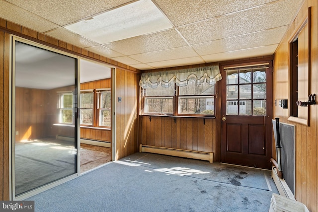 unfurnished sunroom featuring baseboard heating, plenty of natural light, and a paneled ceiling