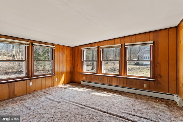 carpeted spare room featuring a baseboard heating unit and wooden walls