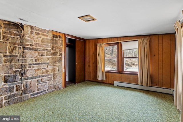 spare room featuring baseboard heating, wooden walls, and carpet floors