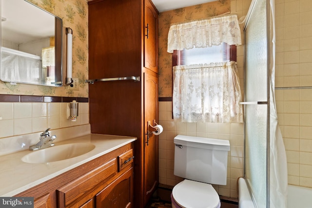 full bathroom featuring a wainscoted wall, toilet, tile walls, wallpapered walls, and vanity