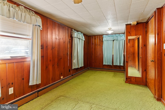 spare room featuring baseboard heating and wood walls