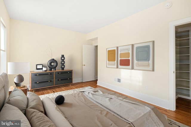 bedroom featuring wood finished floors, visible vents, baseboards, a closet, and a walk in closet