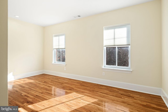 unfurnished room featuring recessed lighting, wood finished floors, visible vents, and baseboards