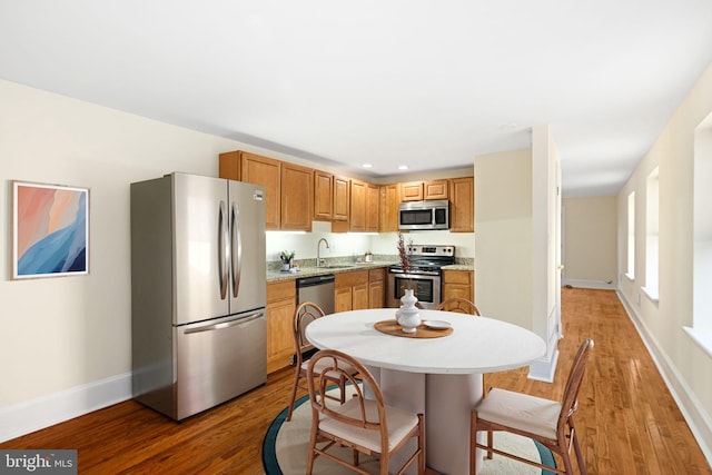 kitchen with light wood-style flooring, stainless steel appliances, light countertops, and a sink