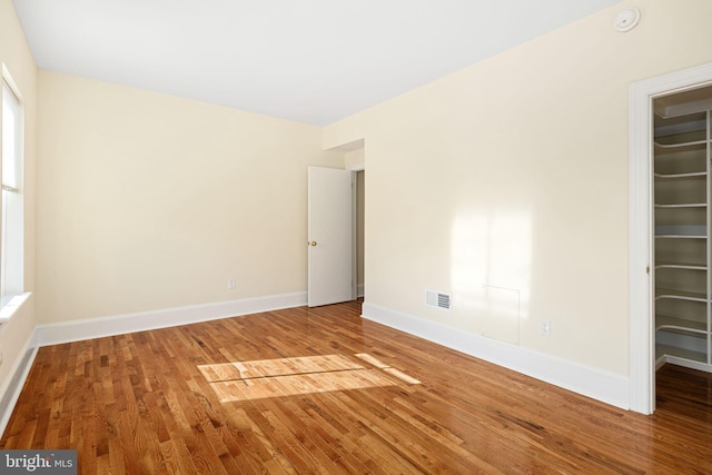 unfurnished room featuring visible vents, baseboards, and wood finished floors