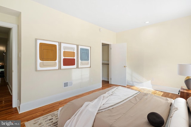 bedroom with wood finished floors, visible vents, and baseboards