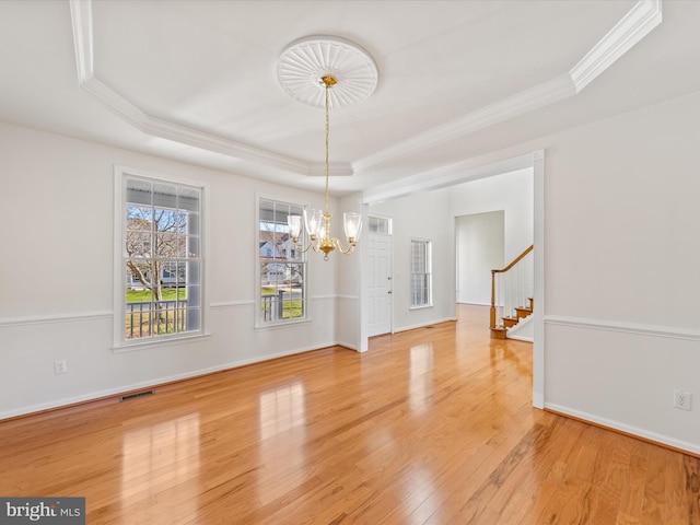 unfurnished dining area featuring light wood-type flooring, visible vents, crown molding, a raised ceiling, and stairs