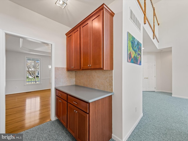 interior space featuring light colored carpet, baseboards, visible vents, and light wood finished floors