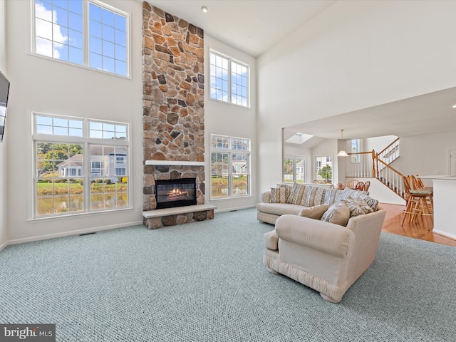 carpeted living area featuring stairs, a high ceiling, a fireplace, and baseboards