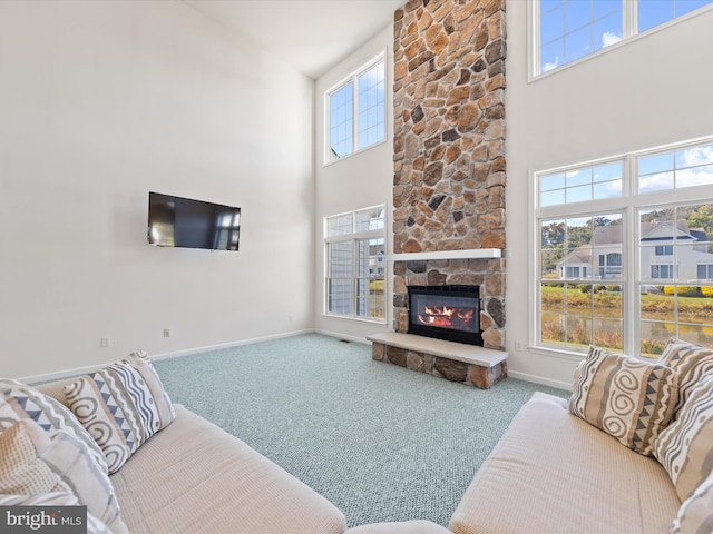 carpeted living room featuring a fireplace, baseboards, and a towering ceiling