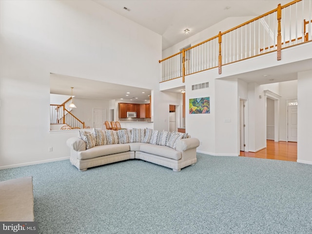 living area with visible vents, carpet floors, baseboards, and stairs