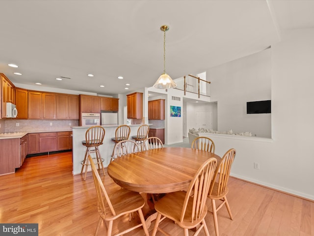 dining room featuring light wood-style flooring, recessed lighting, and baseboards