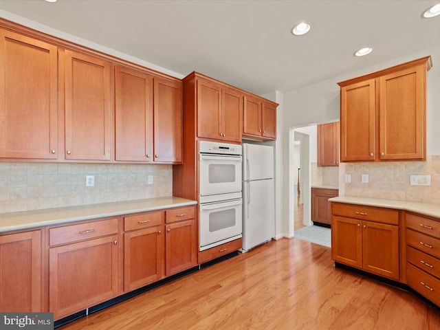 kitchen with white appliances, brown cabinets, light wood-style flooring, and light countertops