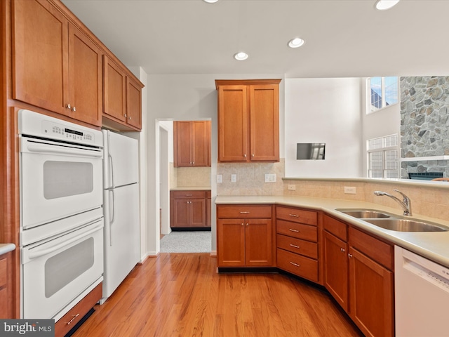 kitchen with tasteful backsplash, white appliances, light countertops, and a sink