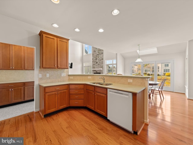 kitchen featuring a sink, dishwasher, a peninsula, and light countertops