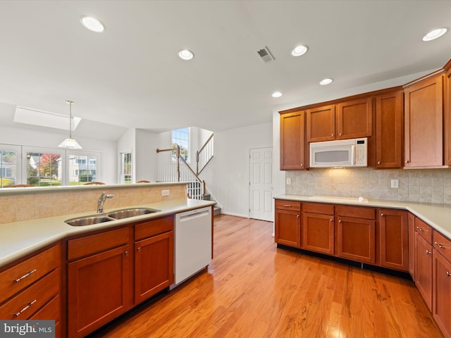 kitchen featuring white appliances, visible vents, a sink, light countertops, and light wood-type flooring