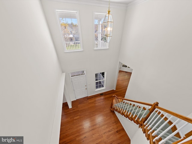 stairway featuring crown molding, an inviting chandelier, and wood finished floors