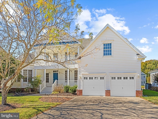 view of front of property with aphalt driveway, a porch, a front yard, central AC, and a balcony