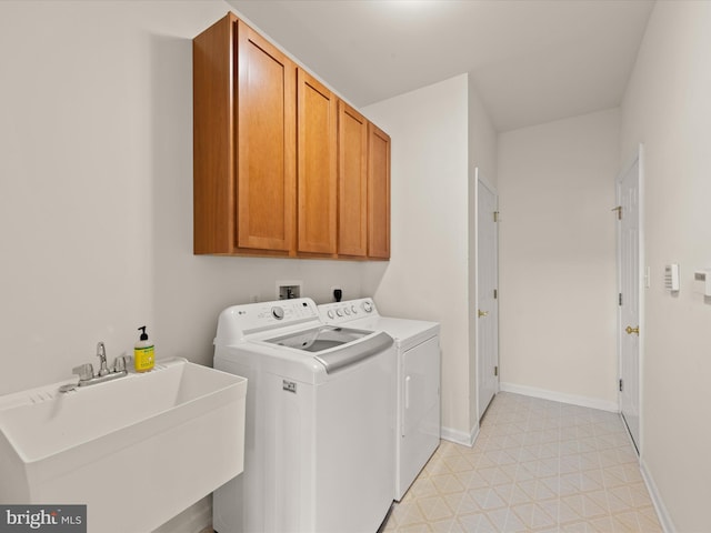 laundry room with baseboards, light floors, washer and dryer, cabinet space, and a sink