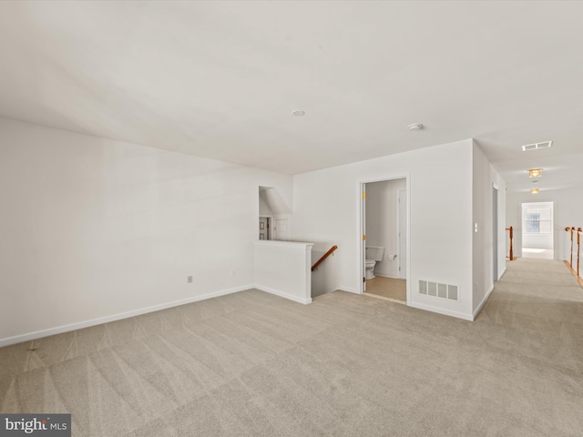 unfurnished room with visible vents, light carpet, and baseboards