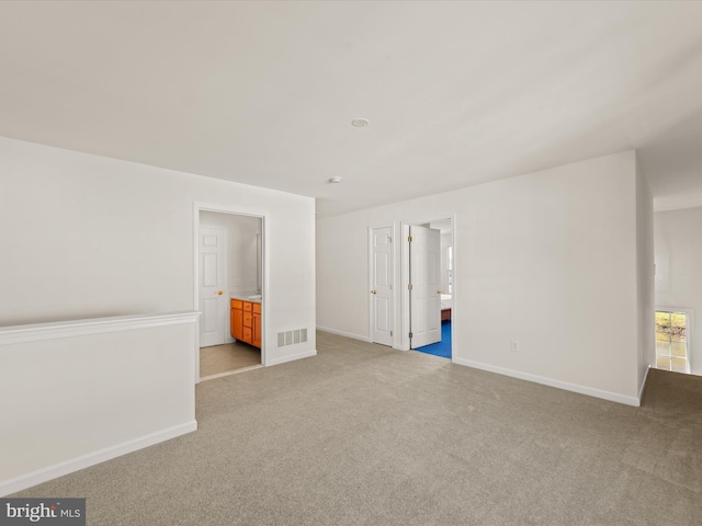 unfurnished bedroom with visible vents, light colored carpet, and ensuite bathroom